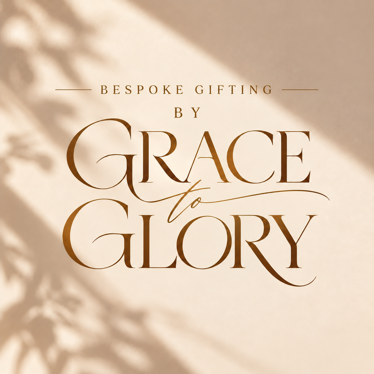 The By Grace to Glory wordmark in bronze on a cream wall, with soft leaf shadows